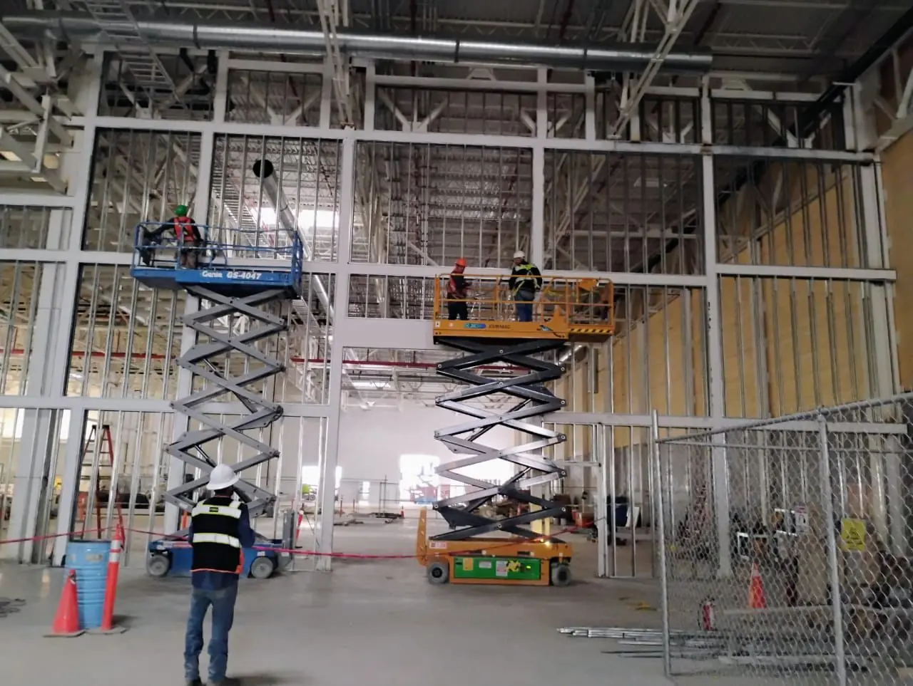 Técnicos de Riker trabajando sobre plataformas de elevación en una nave industrial
